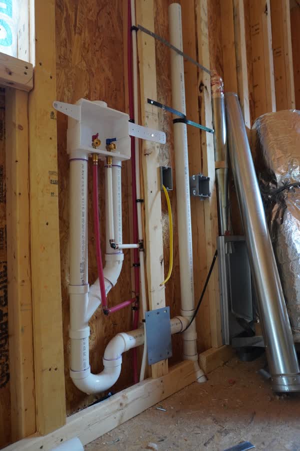 Laundry outlet box with PVC drain and PEX supply lines roughed in between wall studs