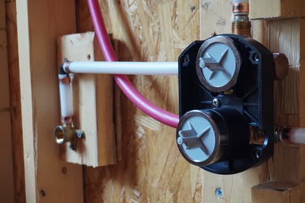 Shower valve rough-in with PEX supply lines and copper stub-outs on a backer board